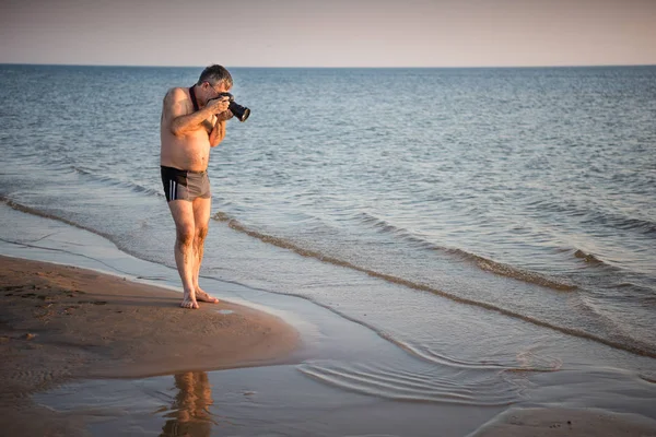 Fotógrafo tomando fotos de conchas en la playa — Foto de Stock