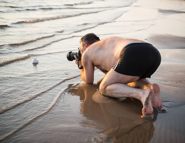 Fotograf na pláži fotografi mušle — Stock fotografie