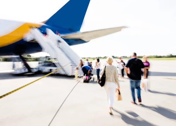 Het wazige beeld van passagiers die naar het vliegtuig lopen — Stockfoto