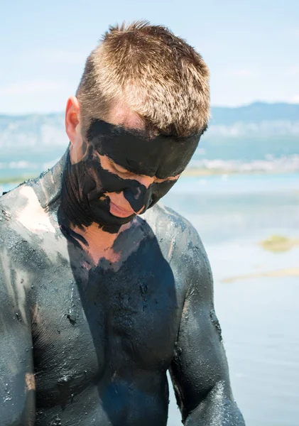 Hombre aplicando arcilla curativa negra —  Fotos de Stock