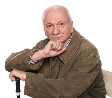 Sandalyede oturan, gözlüklü, sırıtan yaşlı bir adam.