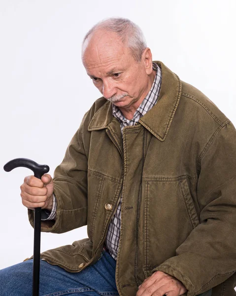 Грустный одинокий пожилой человек с тростью, сидящий на стуле — стоковое фото