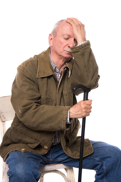 Trauriger, einsamer älterer Mann mit einem Stock auf einem Stuhl sitzend — Stockfoto