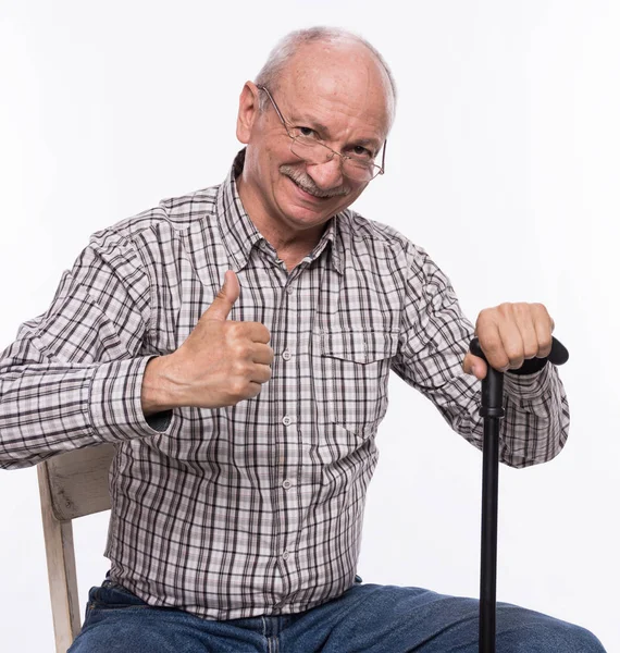 Happy elderly man in glasses with a cane sitting on chair — Stock Photo, Image