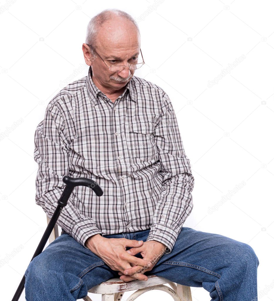 Sad lonely elderly man with a cane sitting  on a chair