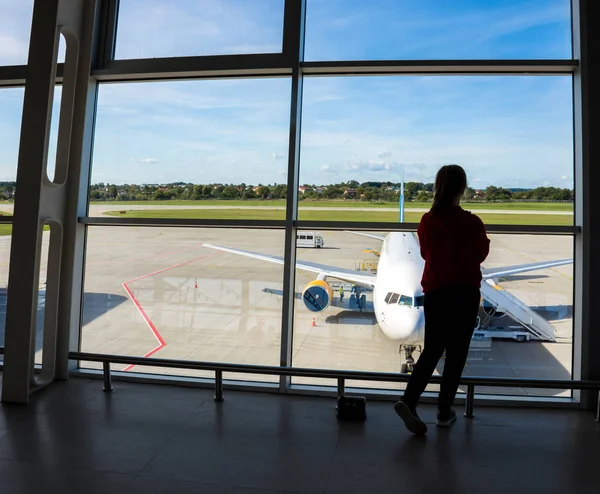 Junge Reisende blickt durch das Flughafenfenster auf pla — Stockfoto