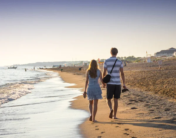 Feliz pareja romántica disfrutando de la puesta de sol a pie en la playa — Foto de Stock