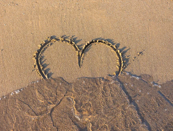 Sinal de coração escrito na areia ao pôr-do-sol . — Fotografia de Stock