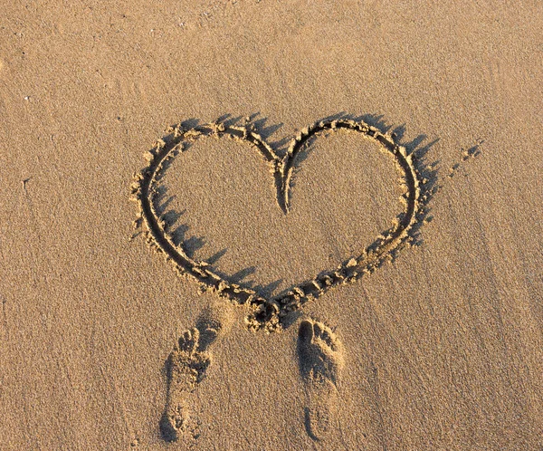 Hart teken schrijven op zand bij zonsondergang. — Stockfoto