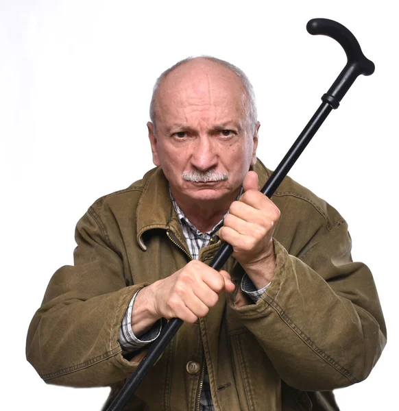 Old angry man threatening with a cane in studio — Stock Photo, Image