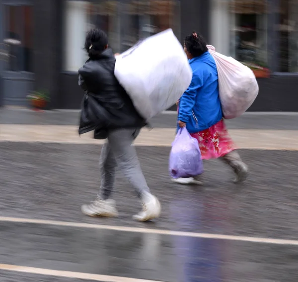 Arme vrouwen slepen zakken in beweging vervagen — Stockfoto