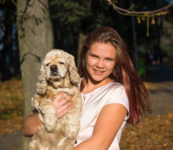 Cute teen girl with a dog posing in summy autumn park — Stockfoto
