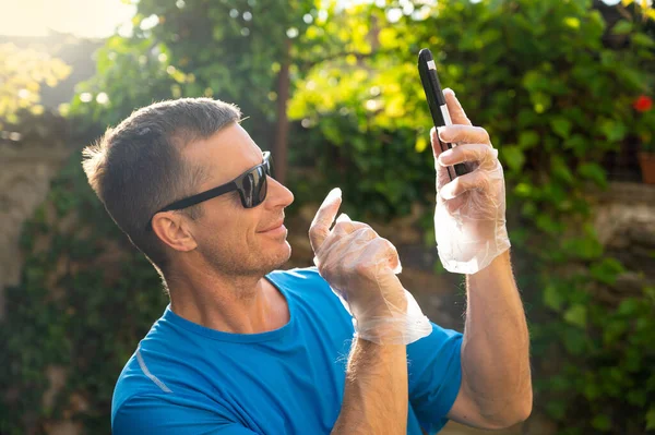 Leende Man Engångshandskar Som Håller Smartphone Utomhus — Stockfoto