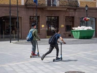 Çocuklar dışarıda scooter kullanıyor.
