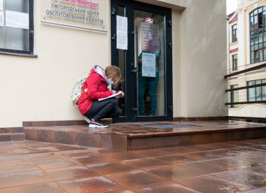 UZHOROD, UKRAINE - Haziran 04, 2020: Ukrayna 'nın Uzhhorod şehrinde karantina sırasında kapıda kuyrukta bekleyen kadın