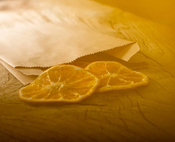 Slices of dried tangerines in craft package on a wooden background