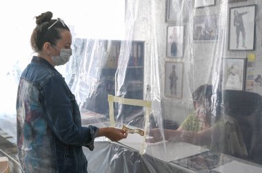 Plastik bariyerin yanındaki kadın kasada nakit para ödüyor. COVID-19 salgını