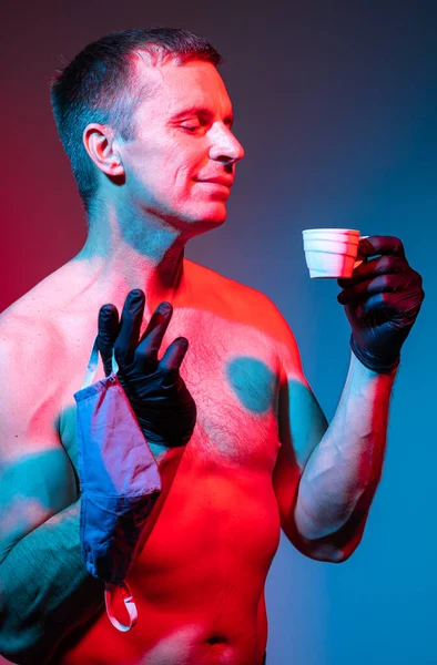 コーヒーを楽しむ保護手袋とフェイスマスクでハンサムな裸の男 — ストック写真