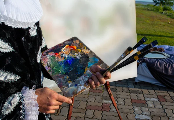 Artist with brushes and palette in hand closeup