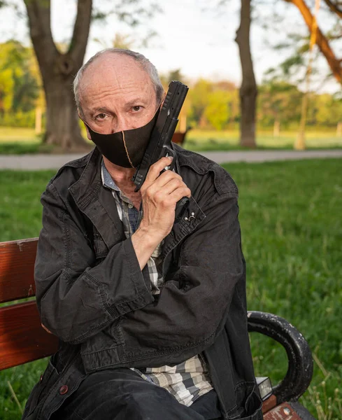 Homem Sênior Máscara Com Uma Arma Sentada Banco Livre — Fotografia de Stock