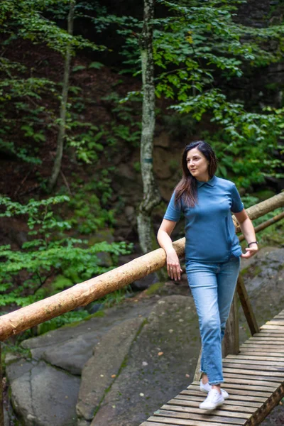 Ormanda tahta bir köprüde poz veren kadın.