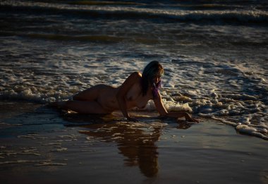 Denizde poz veren güzel çıplak genç bir kadın. Çıplakken seksi Yazın sahilde eğleniyor