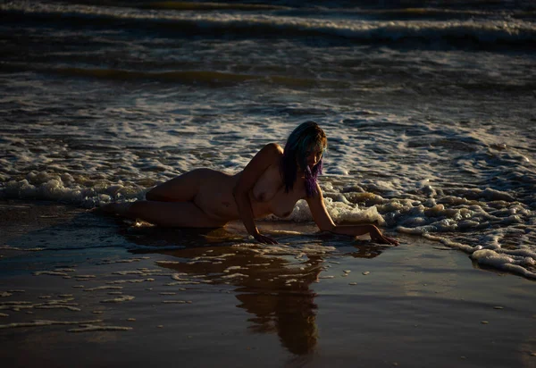 Denizde poz veren güzel çıplak genç bir kadın. Çıplakken seksi Yazın sahilde eğleniyor
