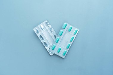 Mavi arka planda tabletlerden su toplamış boş şişliklere karşı. Tıbbi, çevresel konsept. Sağlık terapisi. Salgın, salgın, aşı..