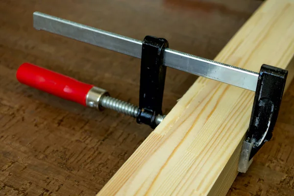 Close up of the process of cutting wooden slats fixed with clamps lying on the dark floor of cork. Repair concept Stock Photo