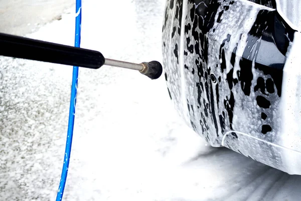 Κοντινό πλάνο του ανθρώπου που κρατά ένα υψηλής πίεσης ψεκαστήρα νερού για πλύσιμο των αυτοκινήτων πόρτα. Απρόσκοπτη αυτο-service πλύσιμο αυτοκινήτων. Αντίληψη απολύμανση και αντισηπτικό καθαρισμό του οχήματος — Φωτογραφία Αρχείου