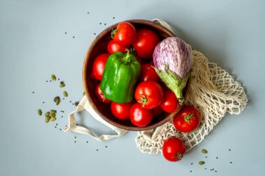 Gri arka planda sağlıklı sebzeler. Geri dönüşüm poşetlerindeki bakkaliyeler. Eko dostu plastik düşük atık yaşam tarzı. Sıfır atık biyolojik gıda depolama ve alışveriş konsepti.