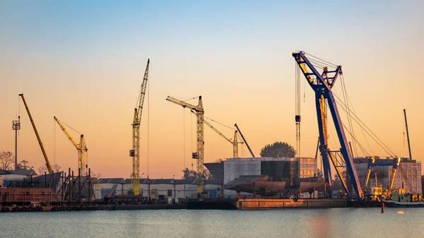 Industrial landscape with shipyard and cranes on river.