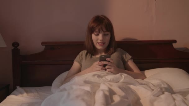 Mulher Bonita Acordando Sentada Sua Cama Com Smartphone Nas Luzes — Vídeo de Stock