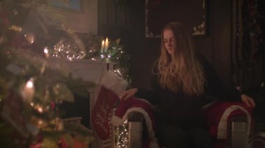 Güzel kız Noel ağacın yanında oturup rahat bir battaniyeye sarılmış