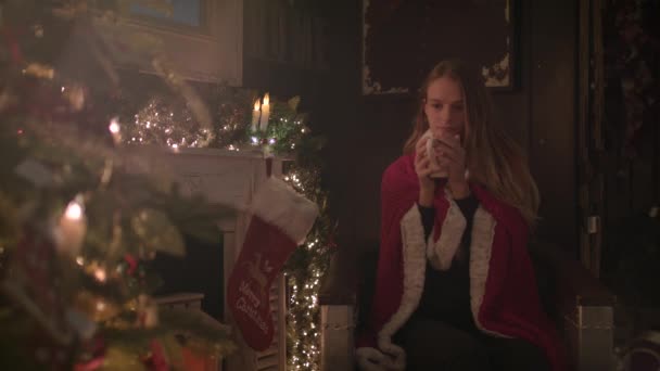 Красивая Девушка Завернутая Уютное Одеяло Сидит Рядом Рождественской Елкой Пьет — стоковое видео