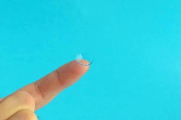 Lentille de contact sur doigt sur fond bleu . — Photo