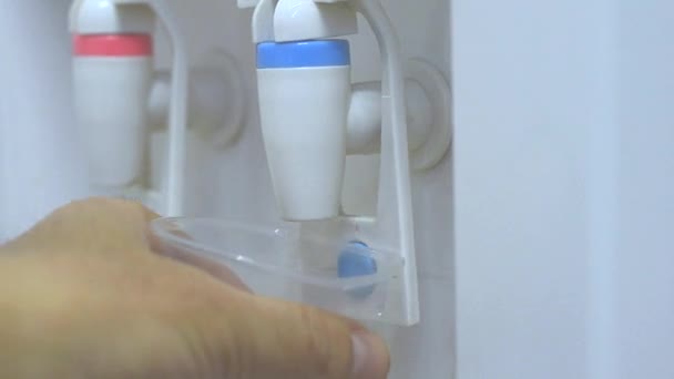 Мужская рука подает холодную воду из кулера в пластиковой чашке — стоковое видео