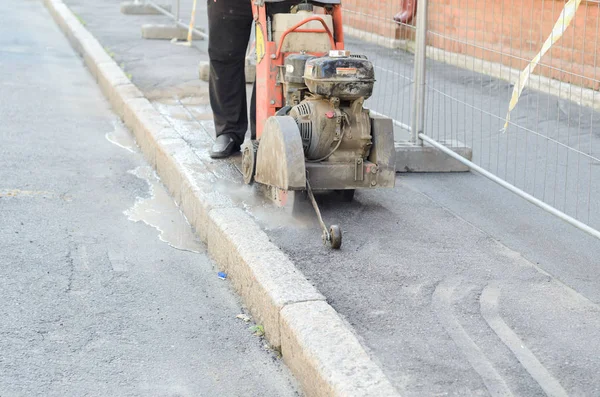 Trabajador de la carretera que corta la carretera de asfalto, trabajando en la reconstrucción de carreteras . Imágenes De Stock Sin Royalties Gratis