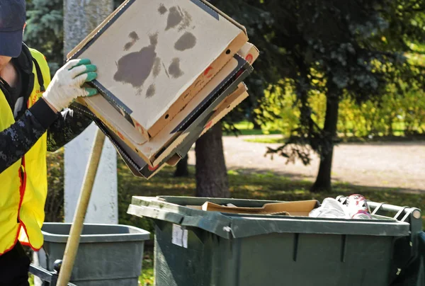 Een conciërge Zet lege pizzadozen in een vuilbak. Stockfoto