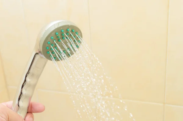 Close up of man holding shower head in the bathroom cabin.A stream of water pours from the shower. — Stock Photo, Image