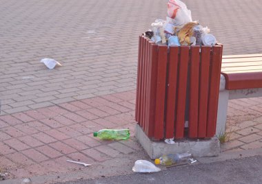 Taş kaldırımda taşan çöp tenekesi. Plastik kirliliği..