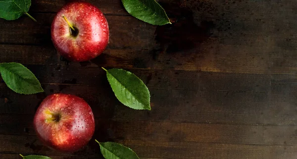 Vista superior, dos manzanas rojas con hojas verdes sobre fondo de madera . — Foto de Stock