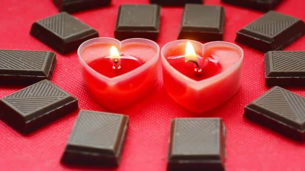 Two love burning hearts with chocolate bars on red background. — Stock Video