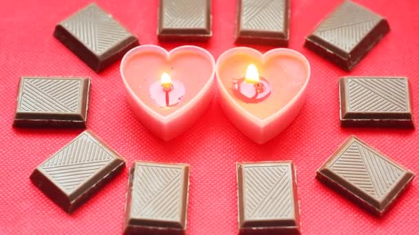 Två kärlek soliga brinnande hjärtan med choklad barer på röd bakgrund. — Stockvideo