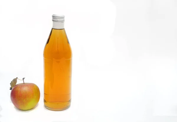 Una manzana entera con hoja y una botella de vinagre de manzana fondo blanco ion, copyspace.. — Foto de Stock