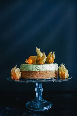 Alkekengi meyve karanlık bir arka plan ile sunulan Matcha cheesecake