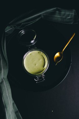 Kavanoz, üç en az karanlık bir arka plan karşı yığını içinde sunulan Matcha cheesecake