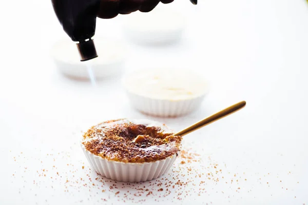 Beyaz bir arka plan üzerinde yanan meşale ile krem brulee üstüne caramelising şeker