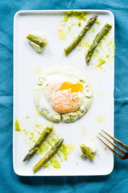 Sous vide haşlanmış yumurta mükemmel tutarlılık için 64,5 derece pişmiş, bir kuşkonmaz püresi ve kuşkonmaz kökleri ile bir çanak dikdörtgen beyaz, düz, üst görünümü, gurme gıda