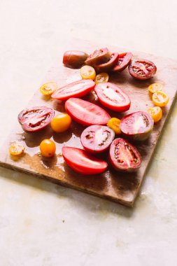 Ahşap bir tahta da kesilmiş farklı domates türleri, doğal ışık. 